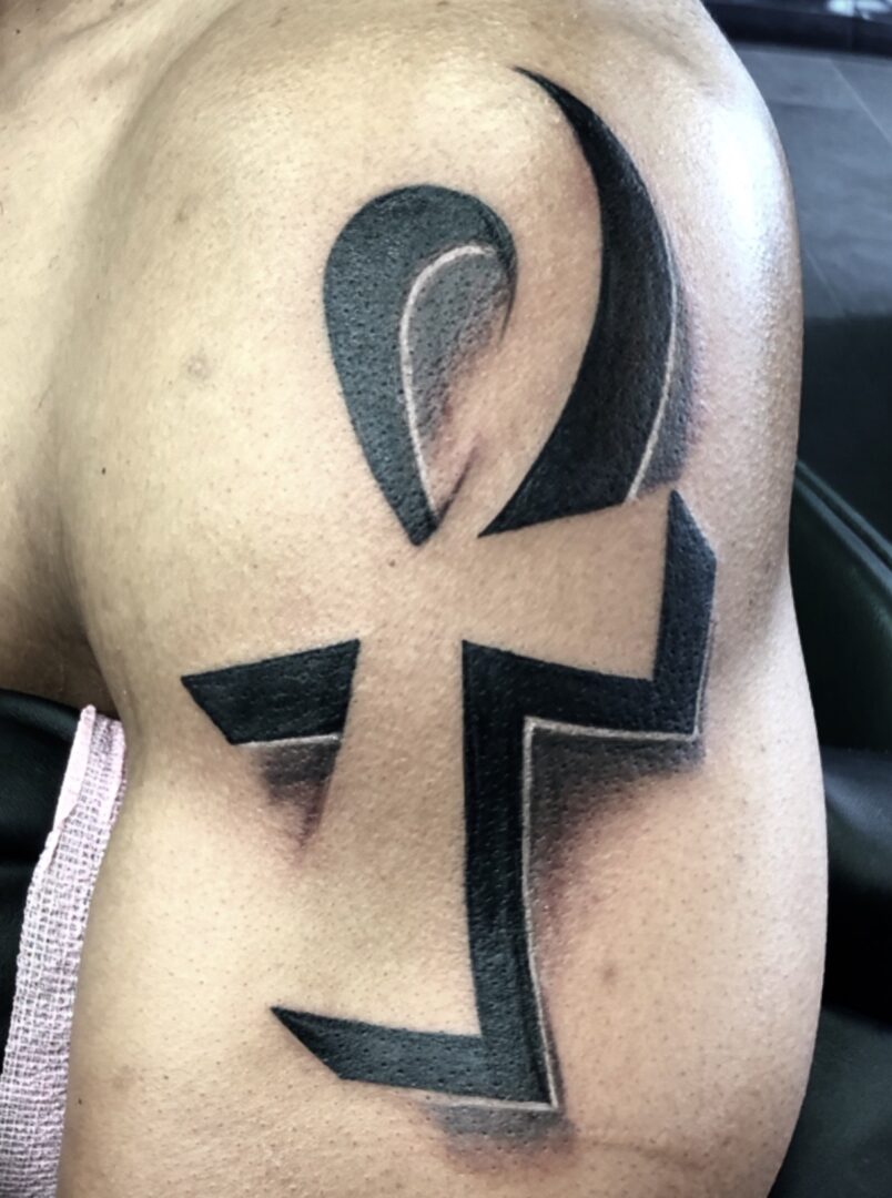 A tattoo of an ankh is shown in black.