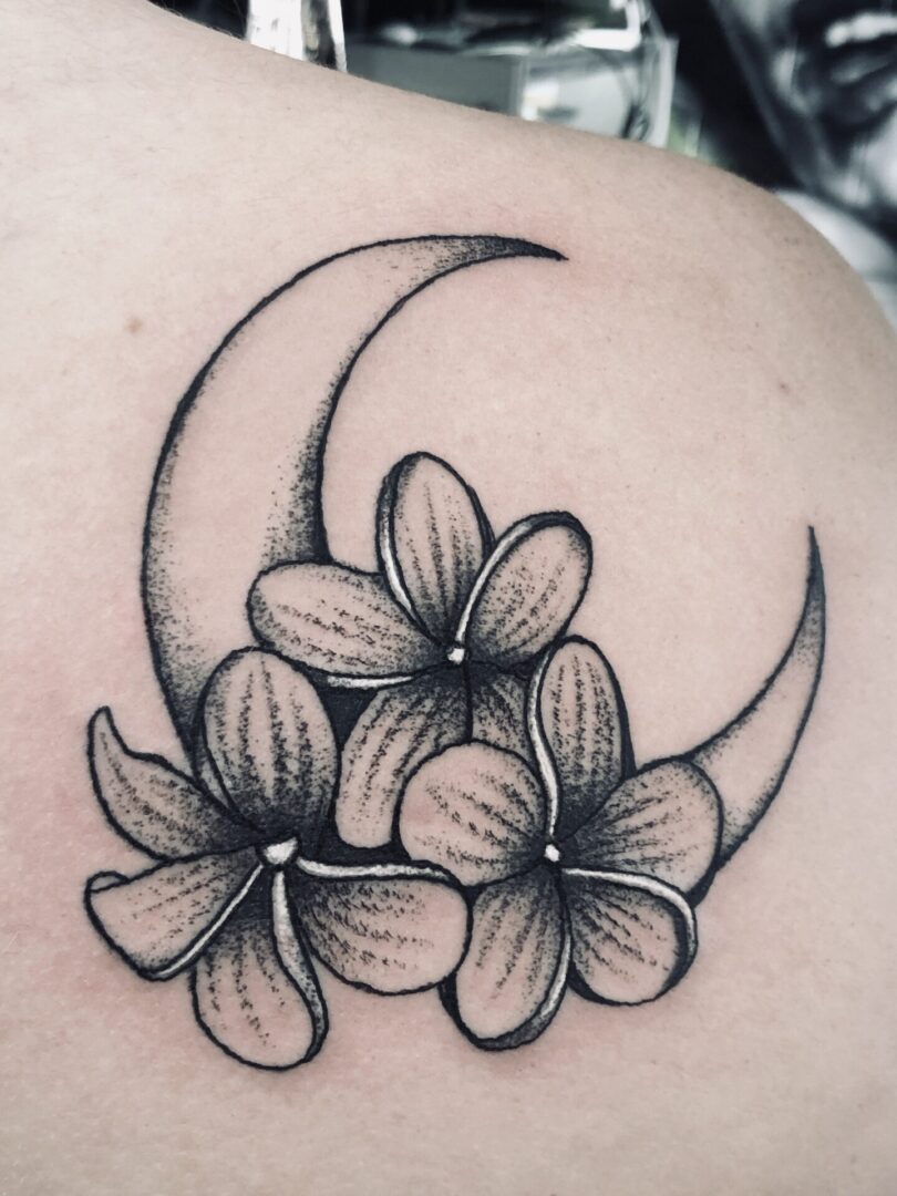 A black and white tattoo of flowers on the shoulder
