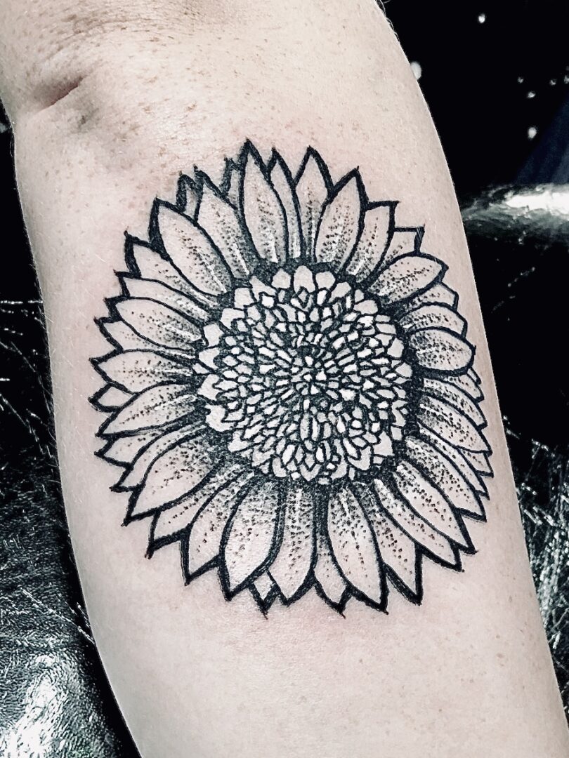 A black and white tattoo of a sunflower.