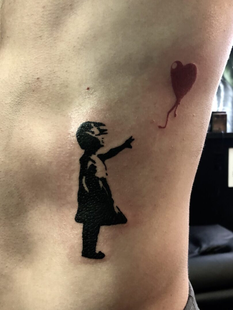 A tattoo of a girl with a balloon on her arm.