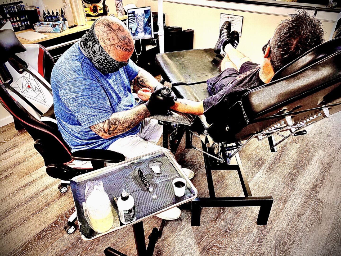 A man getting his tattoo done by another person.