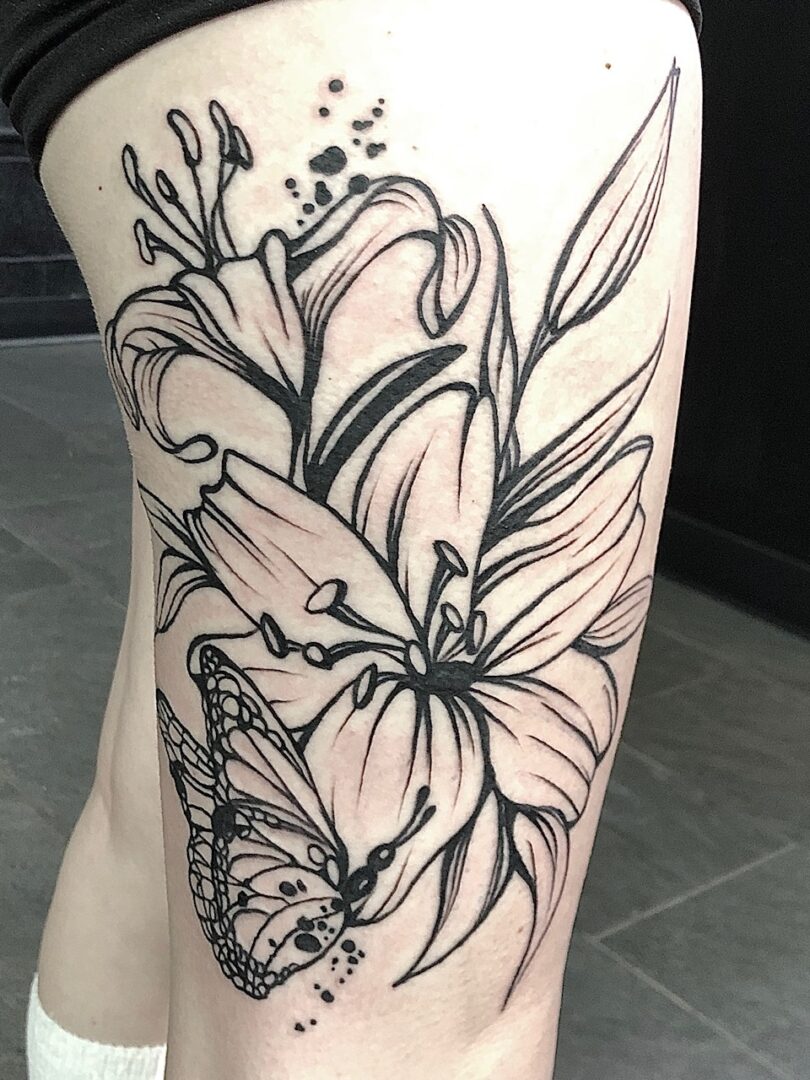 A black and white tattoo of flowers on the leg