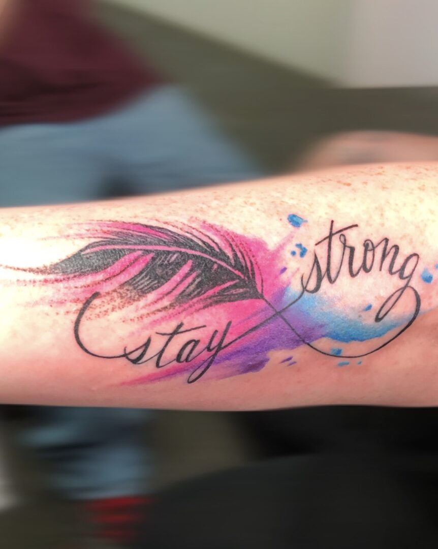 A tattoo that says stay strong with an image of a feather.