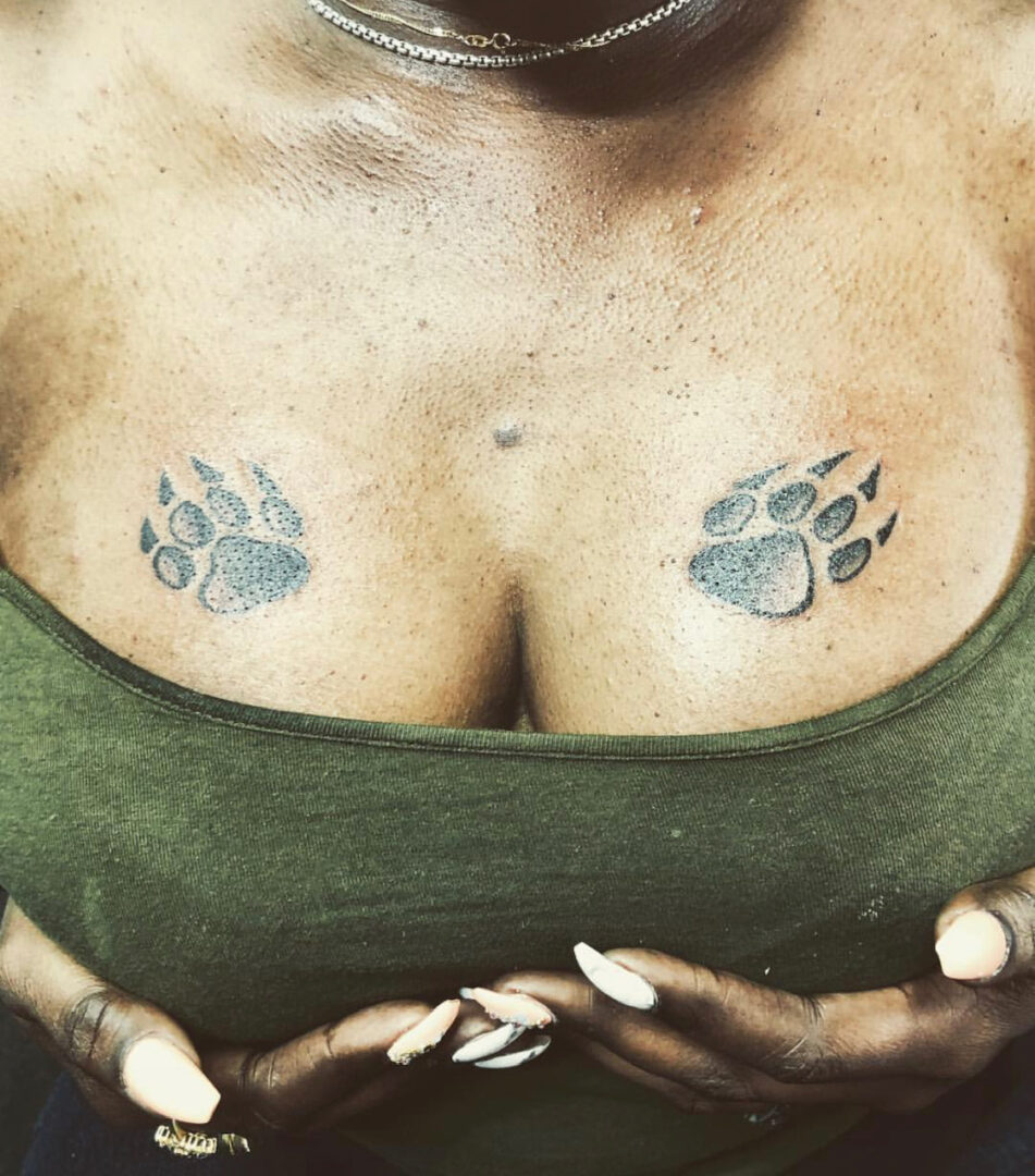 A woman with her hands crossed and her chest tattooed.