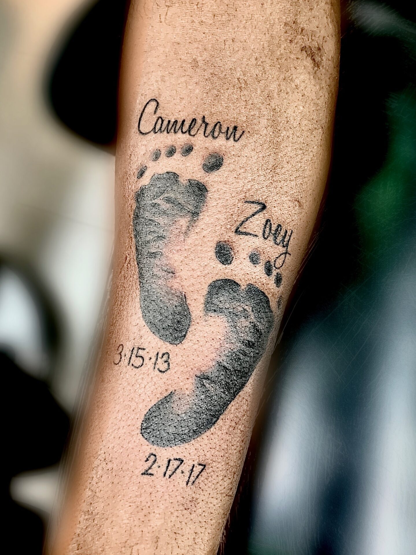 A tattoo of two feet with the date and name cameron zogby.