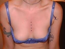 A woman with tattoos on her chest and breast.