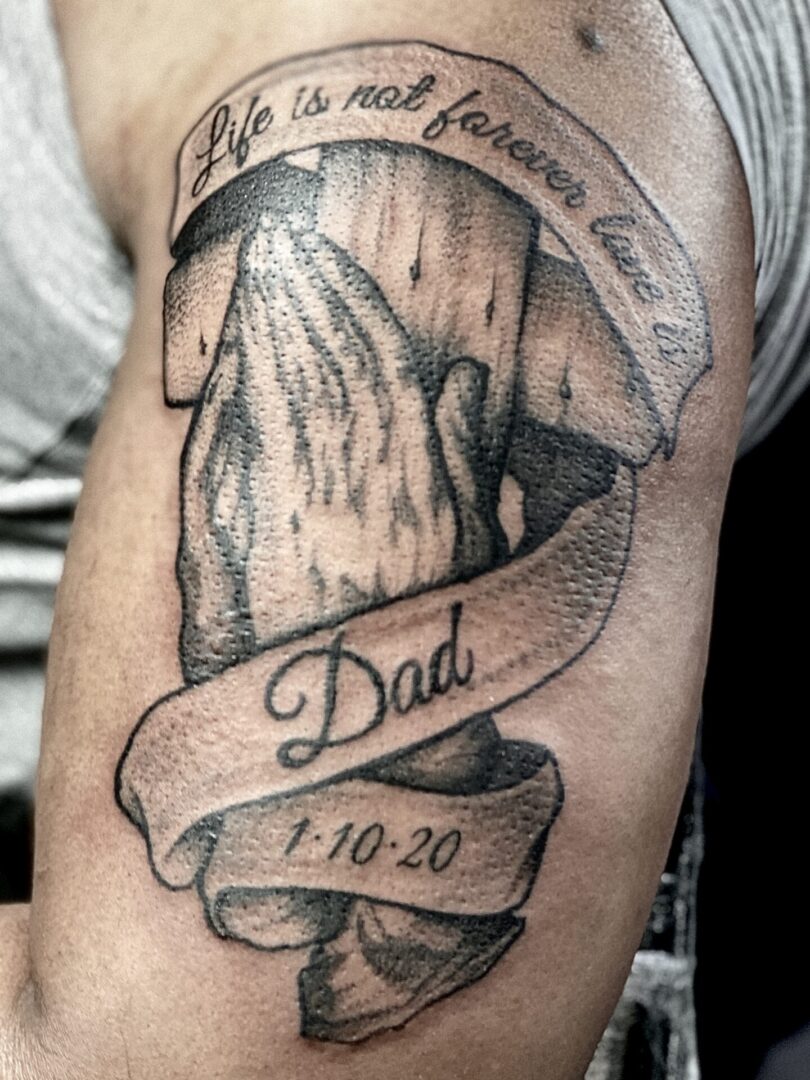 A man 's arm with a tattoo of a wooden cross.
