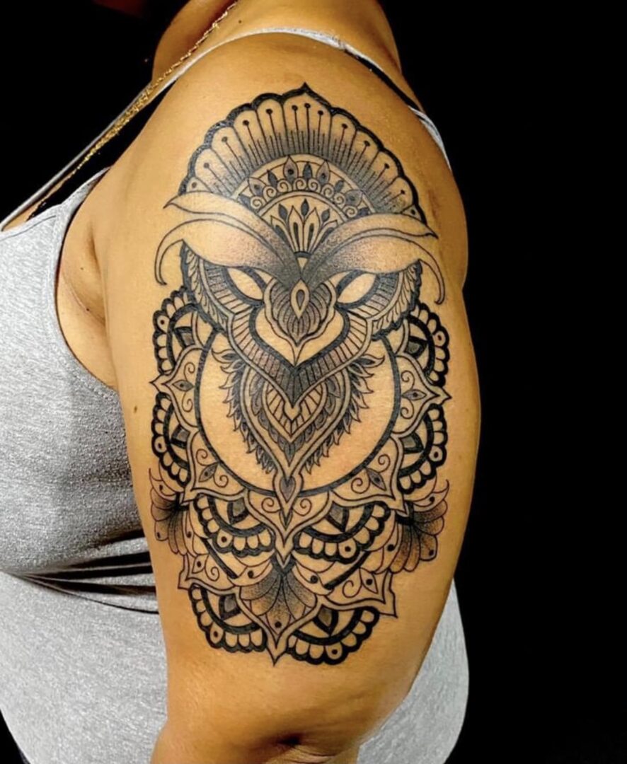 A woman with a tattoo on her shoulder of an owl.