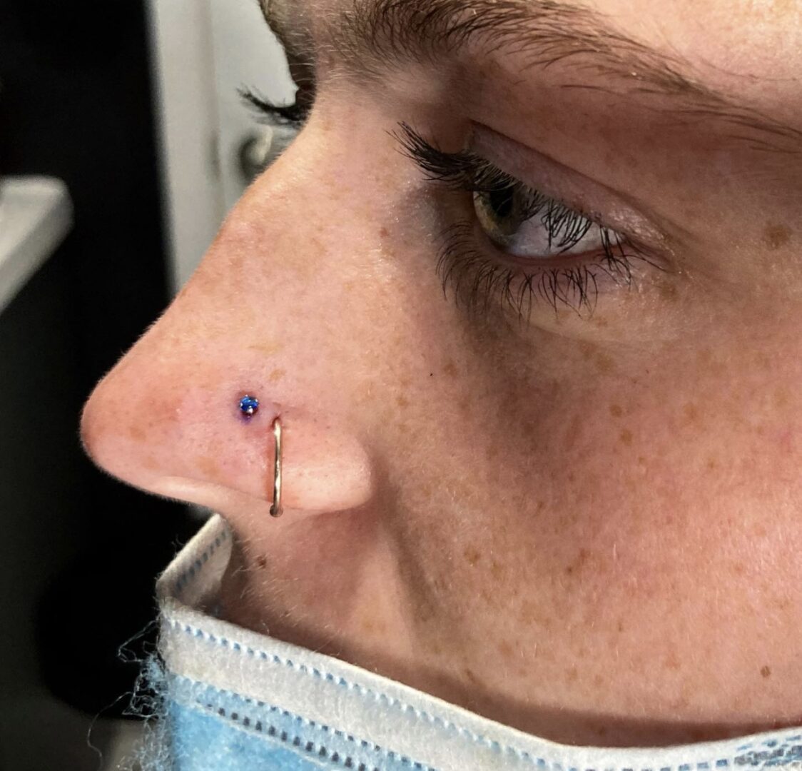 A woman with a nose piercing and blue ink.