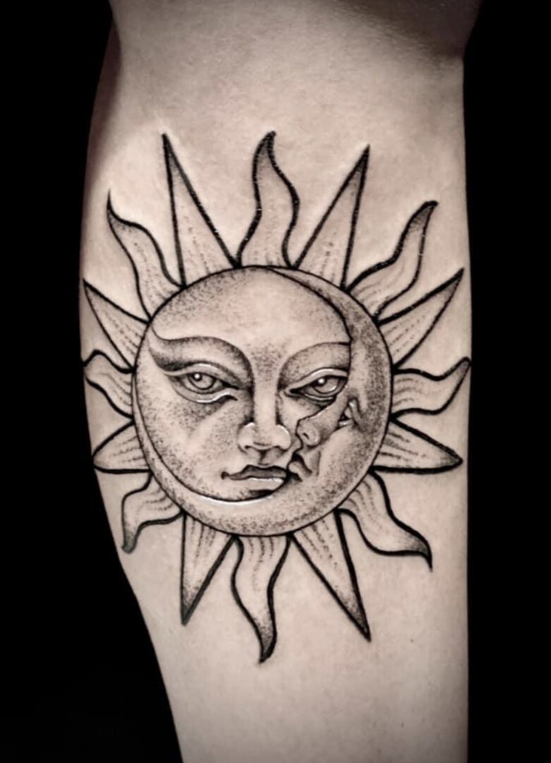 A black and white tattoo of the sun with a face