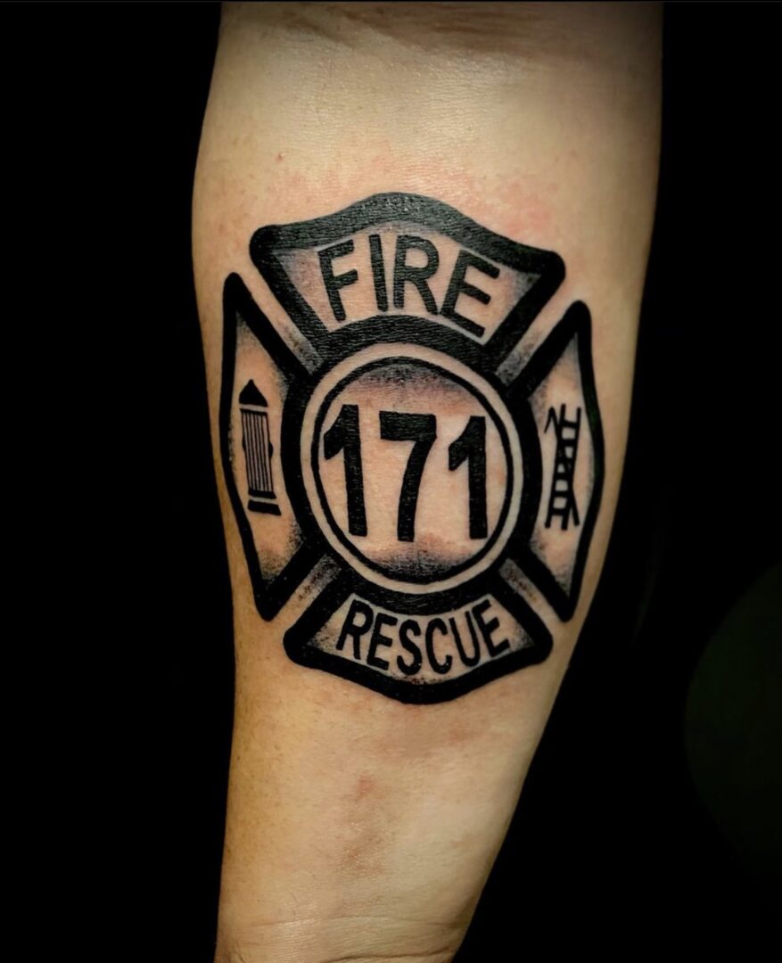 A black and white tattoo of a fire department logo.