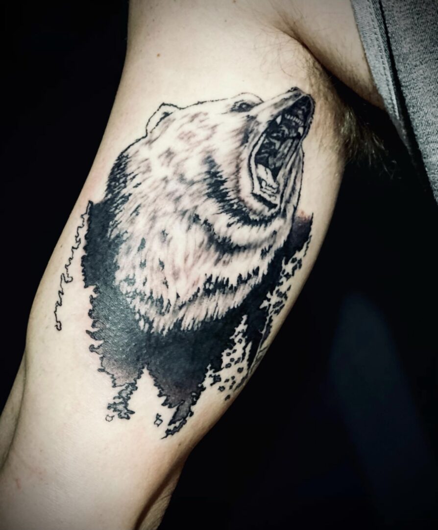 A black and white bear tattoo on the arm of someone.