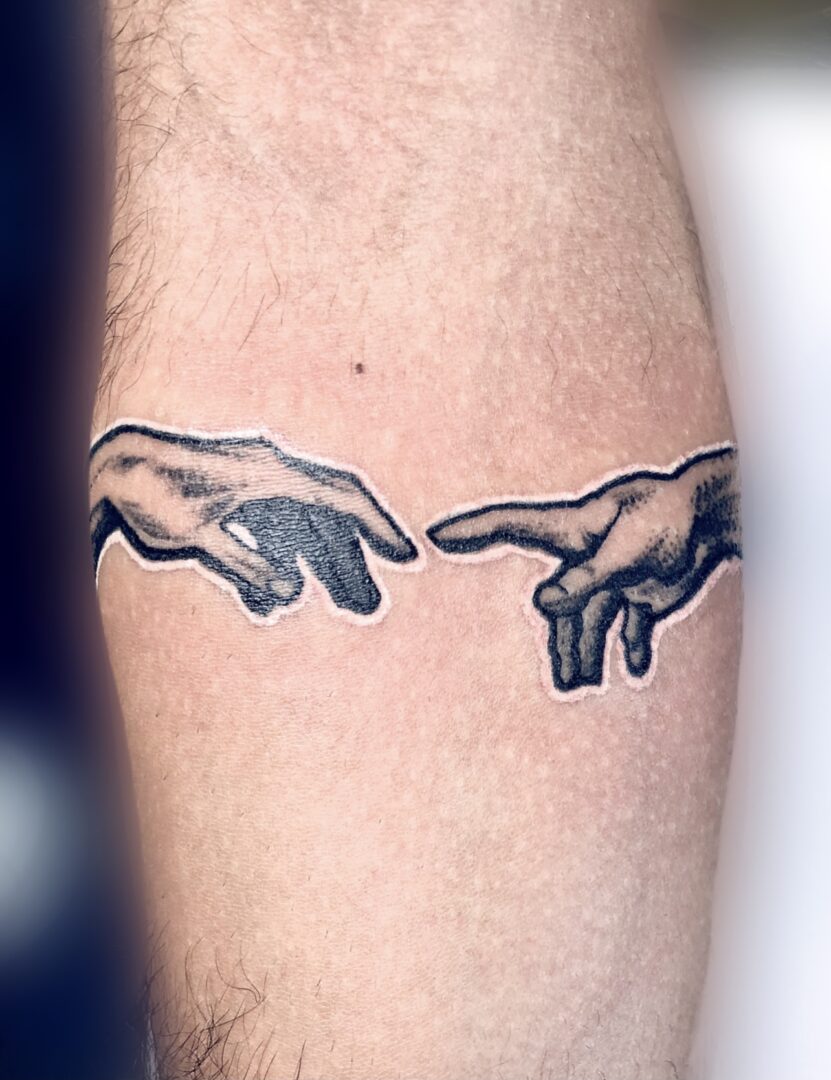 A tattoo of the creation of adam is shown.