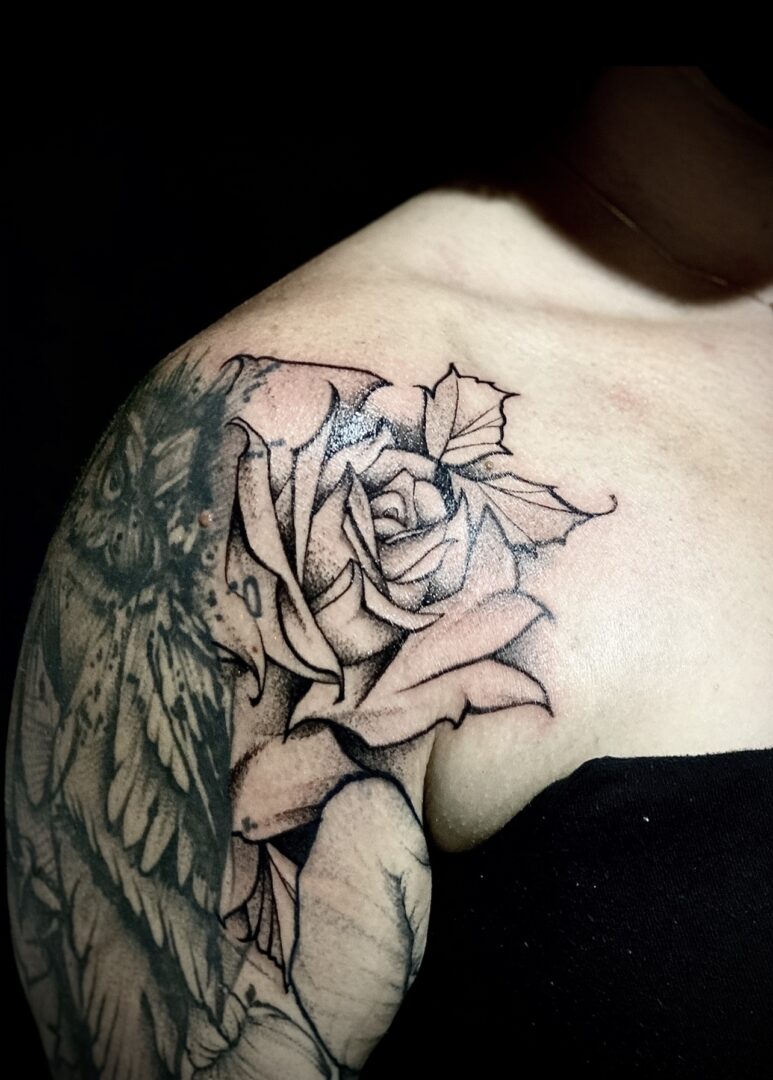 A woman with a tattoo of a rose on her shoulder.