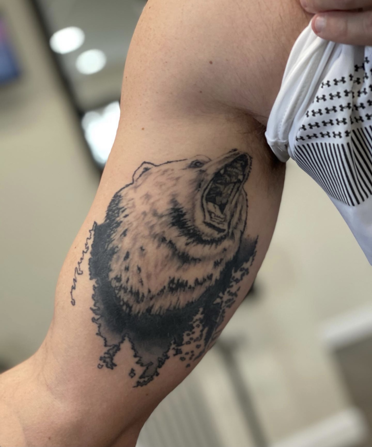 A bear tattoo on the arm of someone.