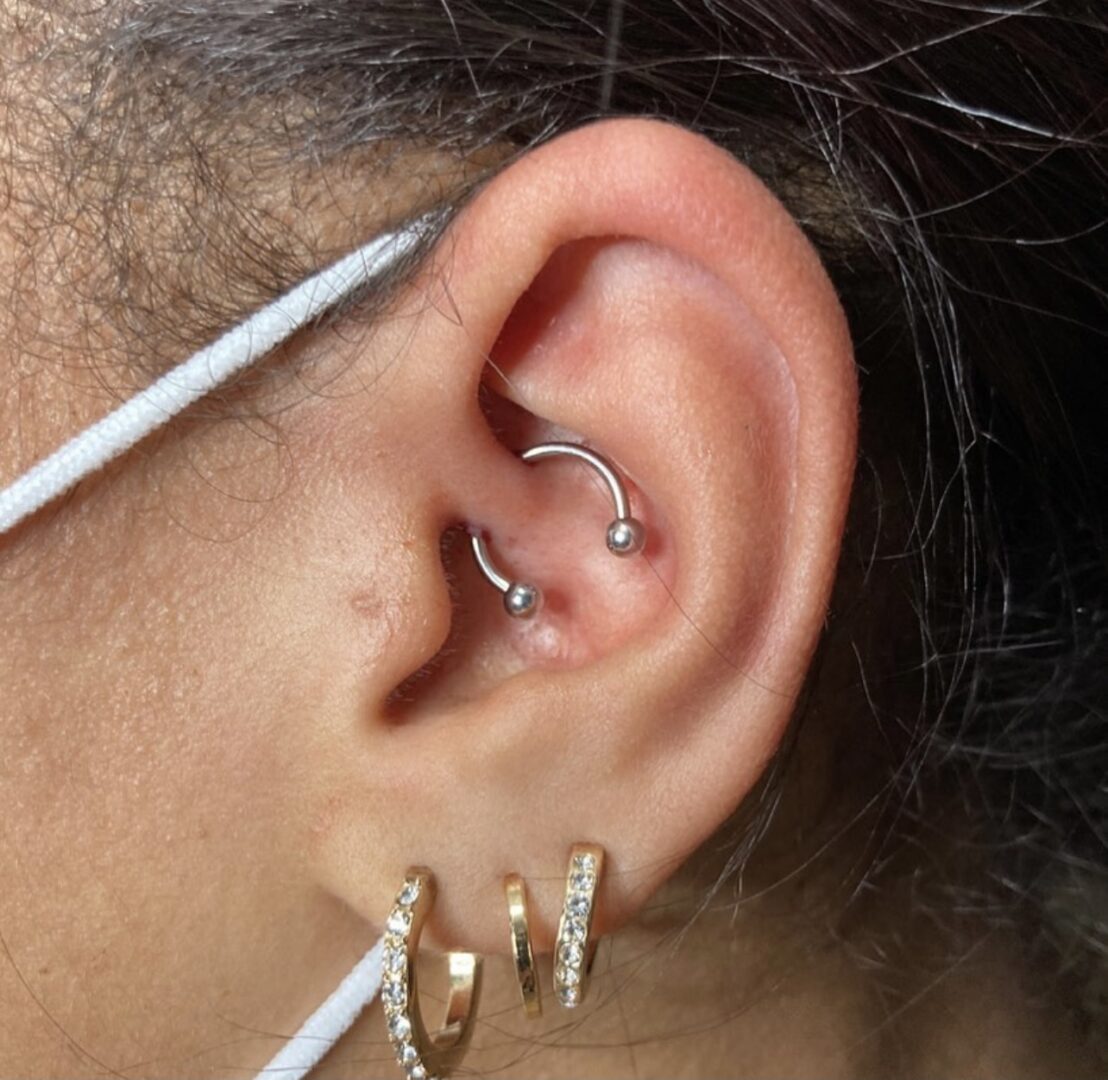 A person with their ear piercings and earrings.