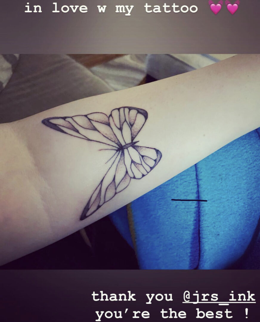 A butterfly tattoo is shown on the arm of someone.