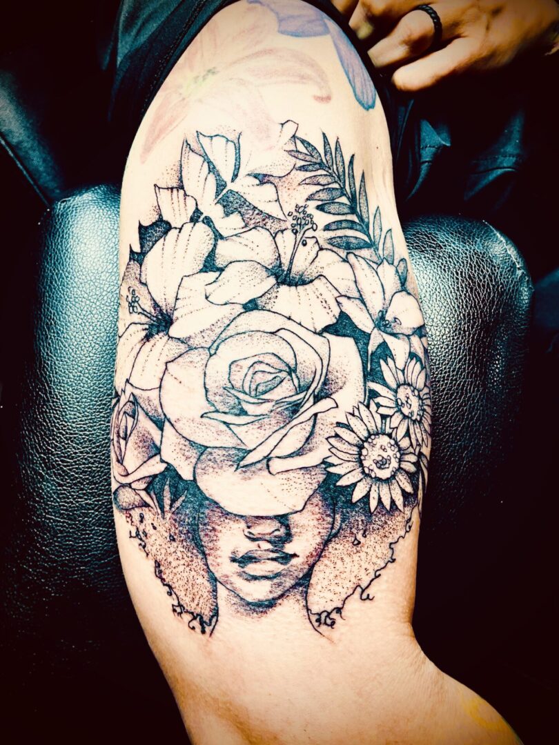 A woman 's face with flowers on her arm.