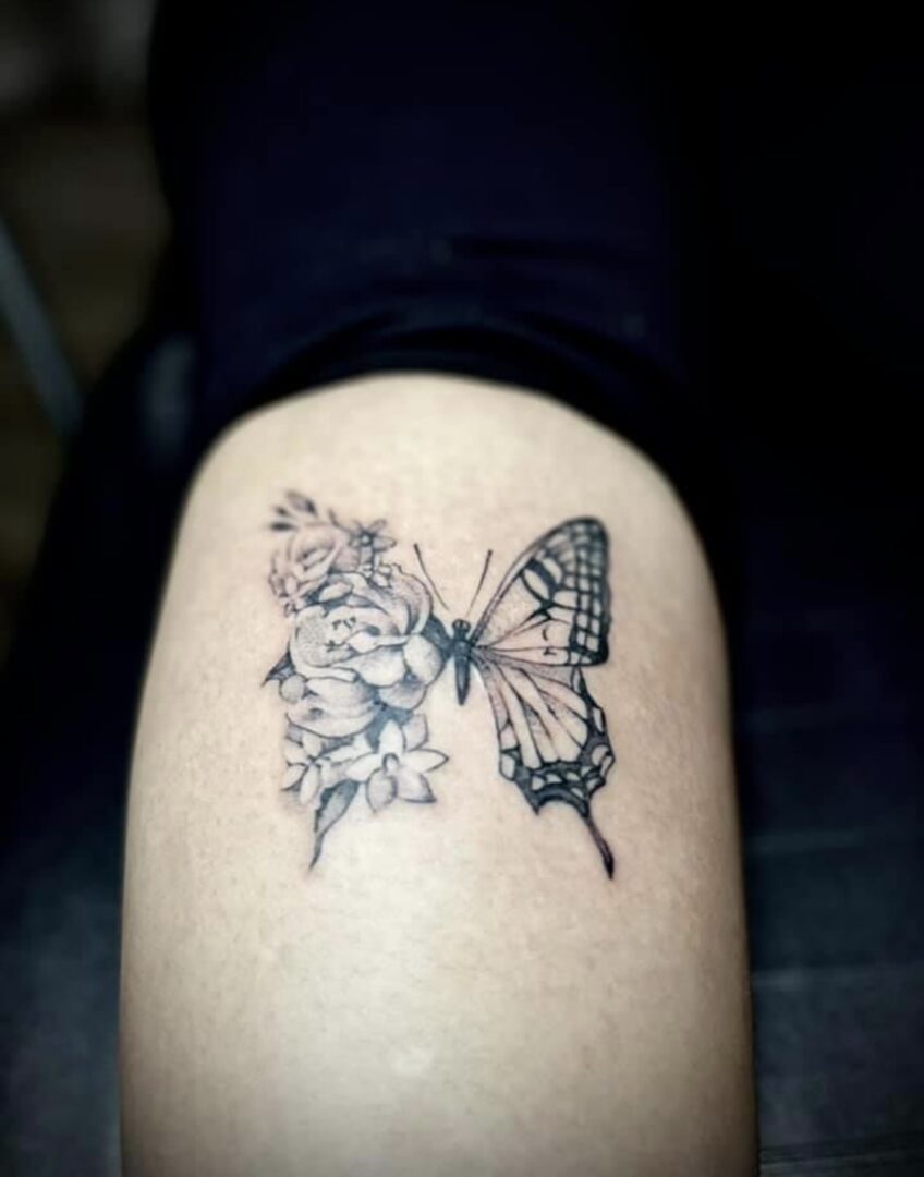 A butterfly tattoo with flowers on the side of it.