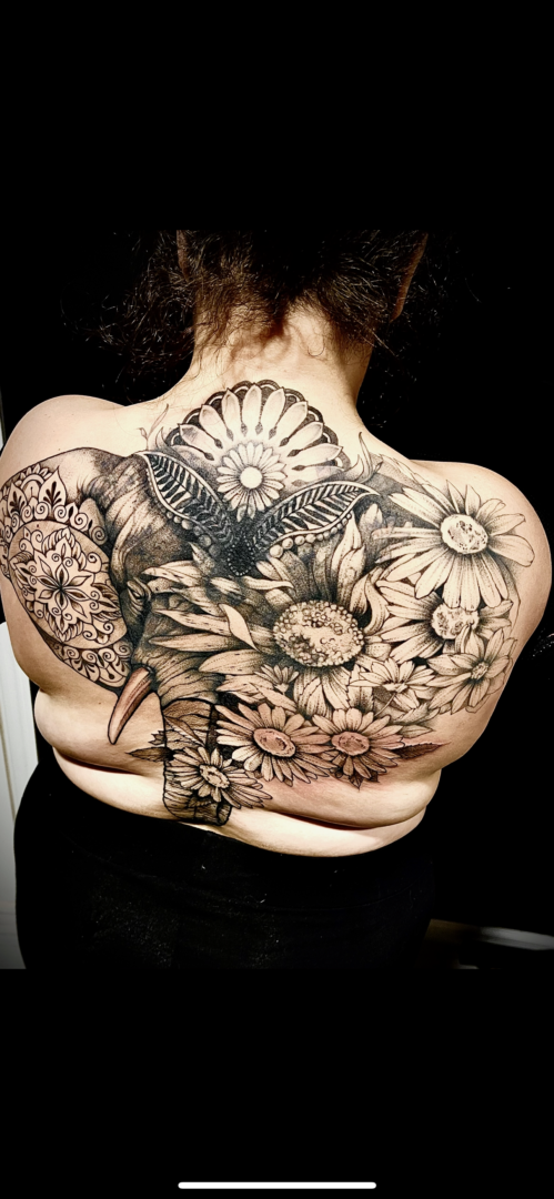 A woman with an elephant and flowers tattoo on her back.