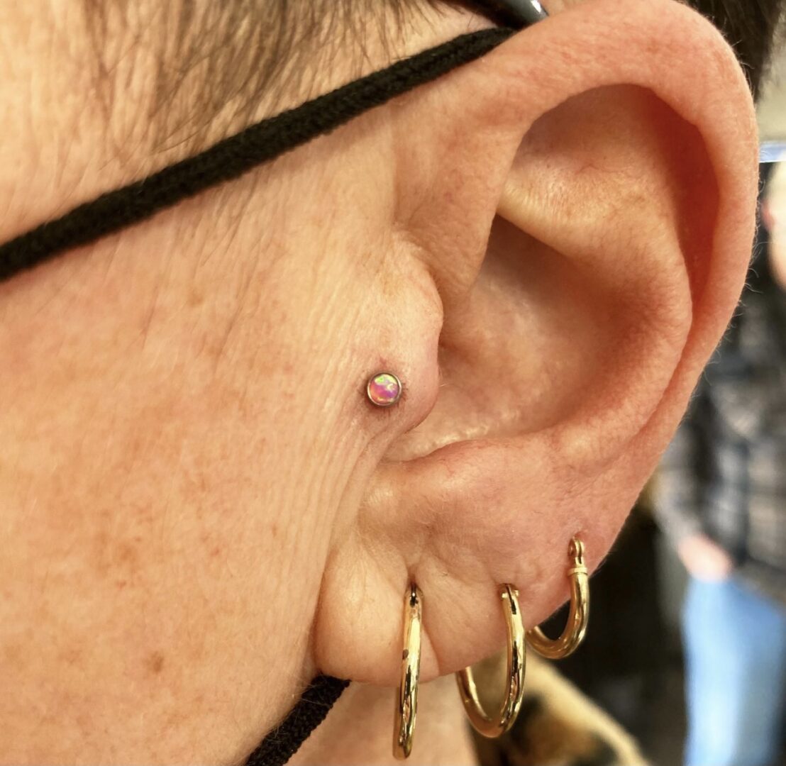 A person with their ear piercings and earring.
