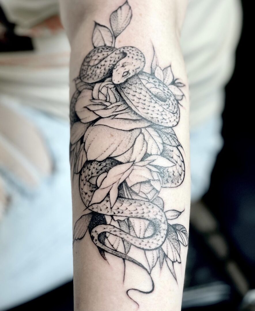 A tattoo of a snake with flowers on it