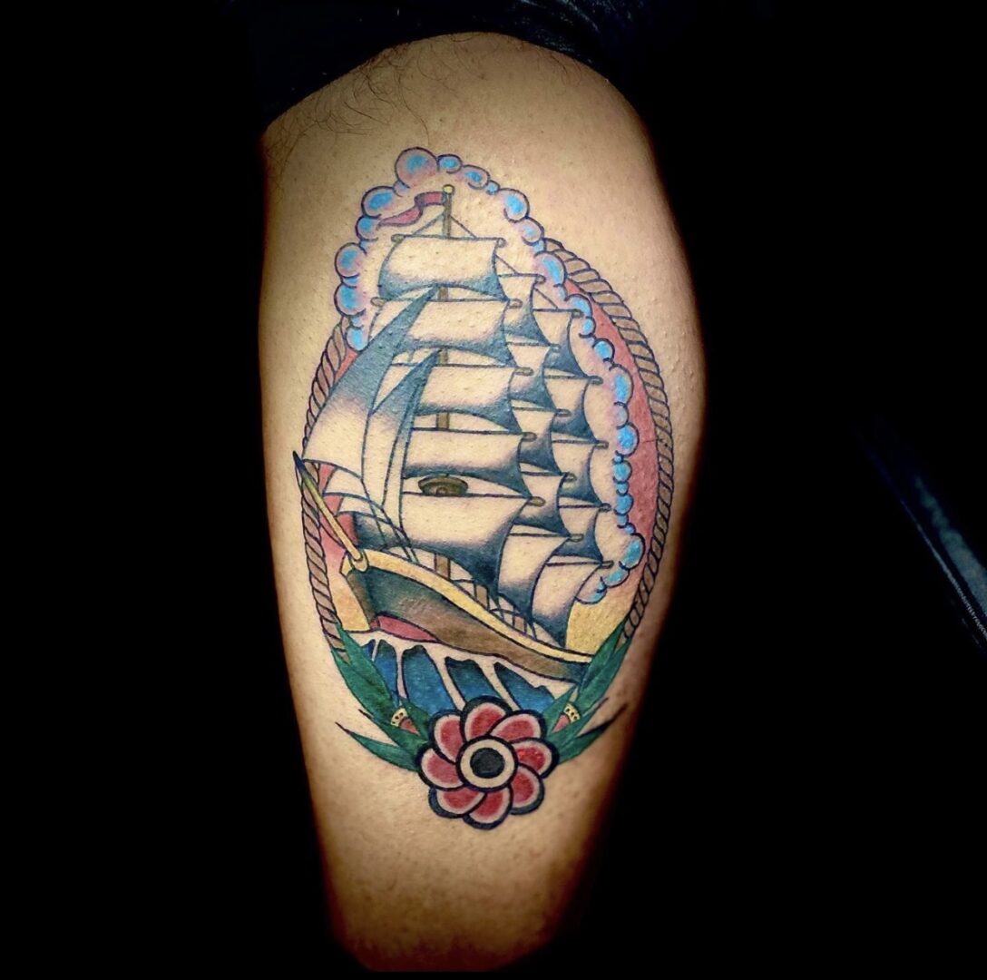 A tattoo of a ship with flowers on it.