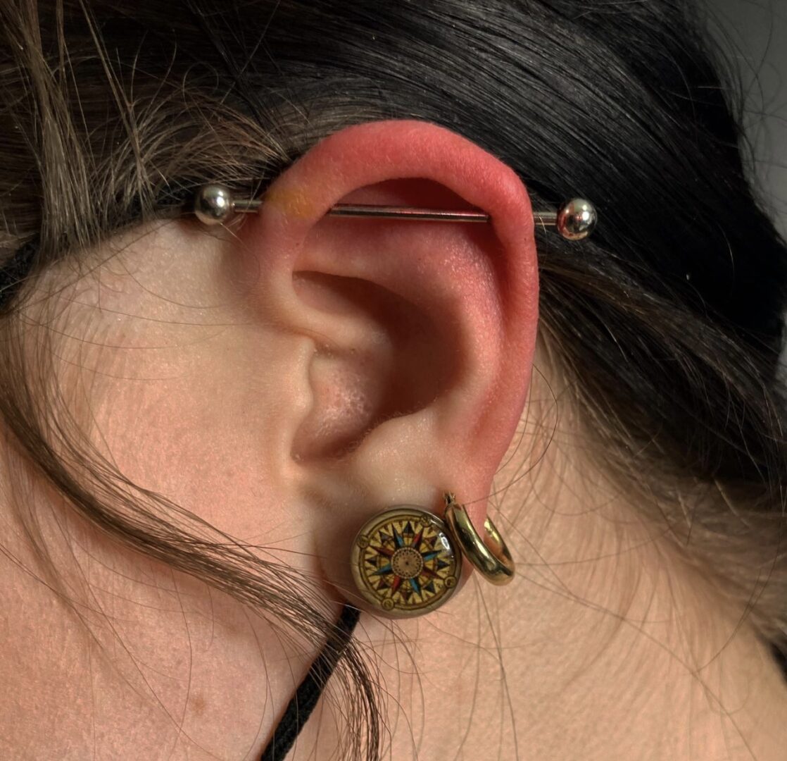 A woman with a black earring and a gold ear clip.