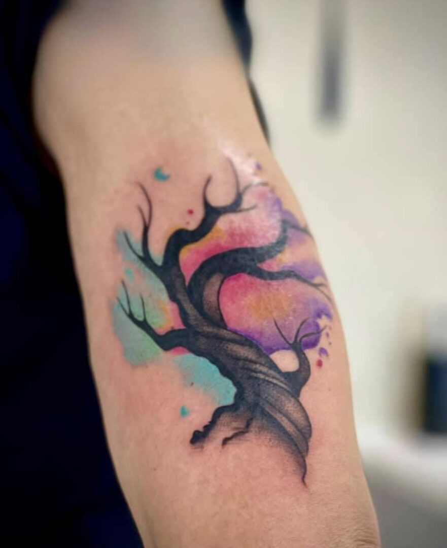 A colorful tree tattoo on the arm of someone.