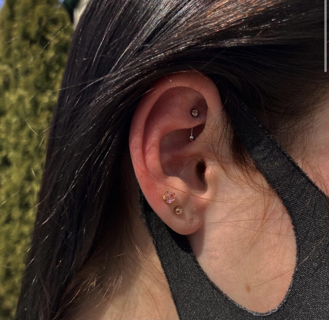 A woman with long hair and black shirt is wearing an ear piercing.