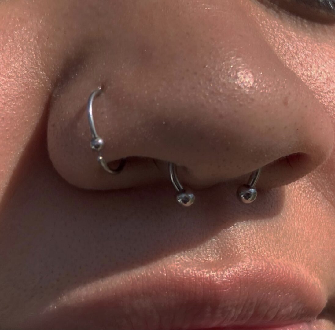 A woman with two small silver hoops in her nose.