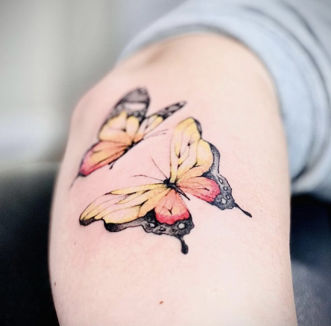 A person with a tattoo of butterflies on their arm.