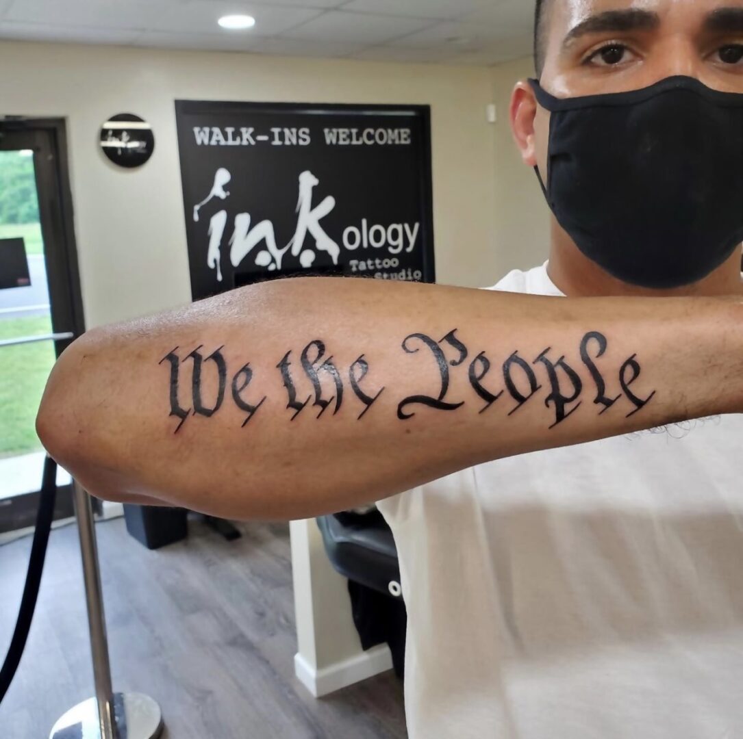 A man with a mask on and a tattoo of the words 