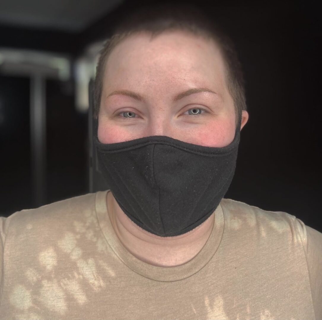 A woman wearing a black face mask.