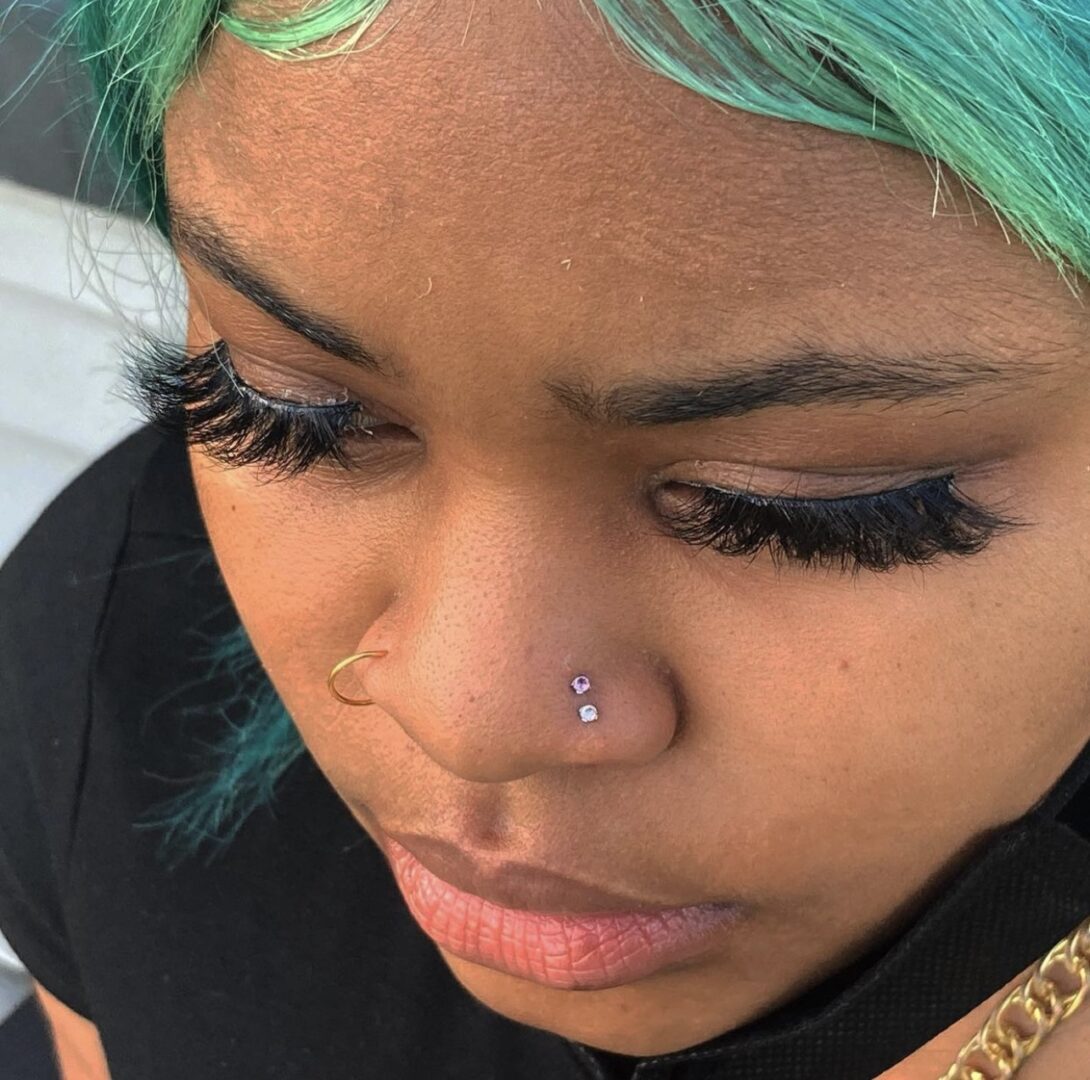 A woman with green hair and piercing in her nose.
