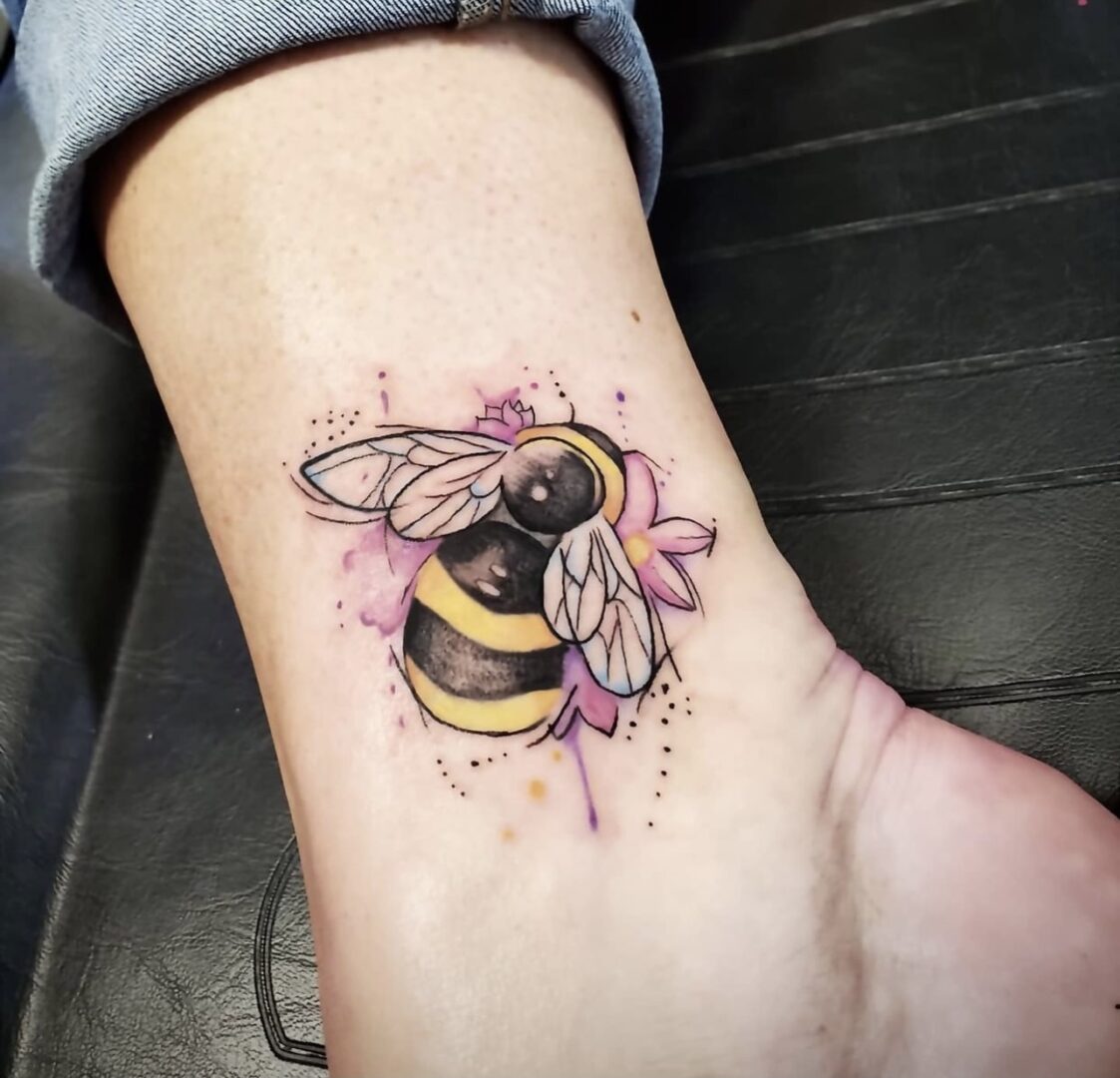 A bee tattoo on the ankle of someone.