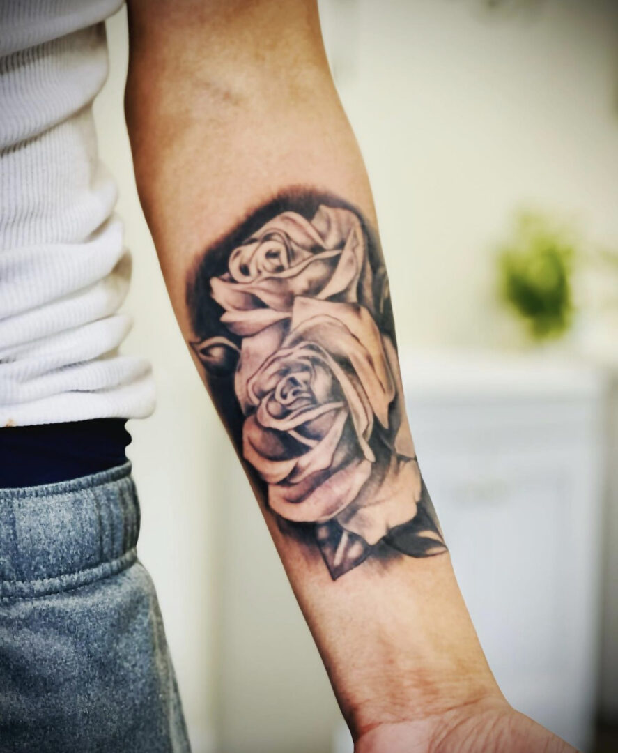 A man with his arm tattooed with roses.