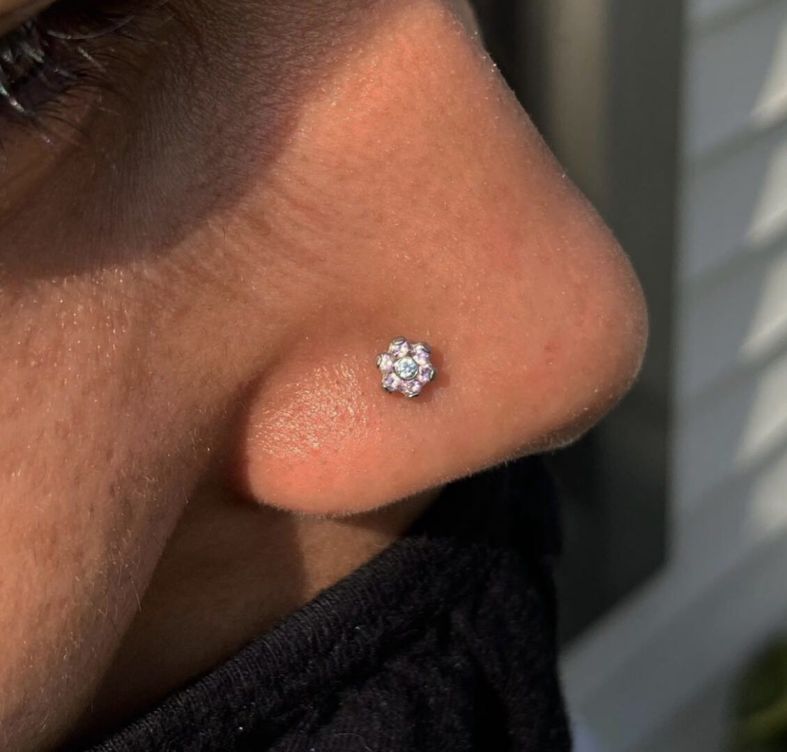 A person with their nose piercing and wearing a black jacket
