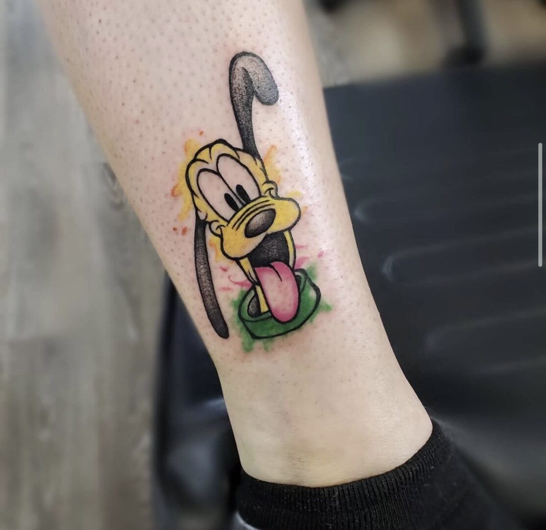 A tattoo of pluto with tongue hanging out.