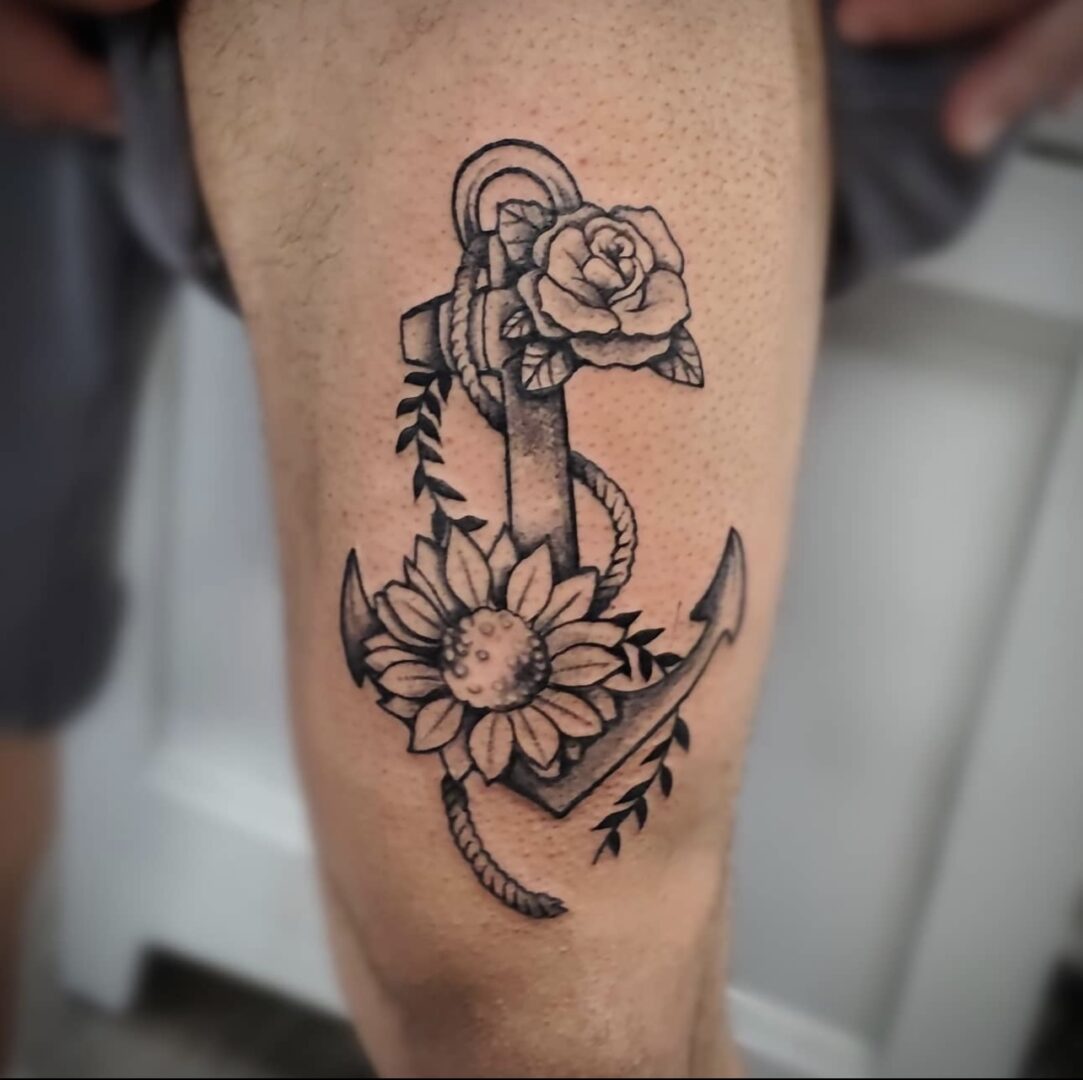 A tattoo of an anchor with flowers on it.