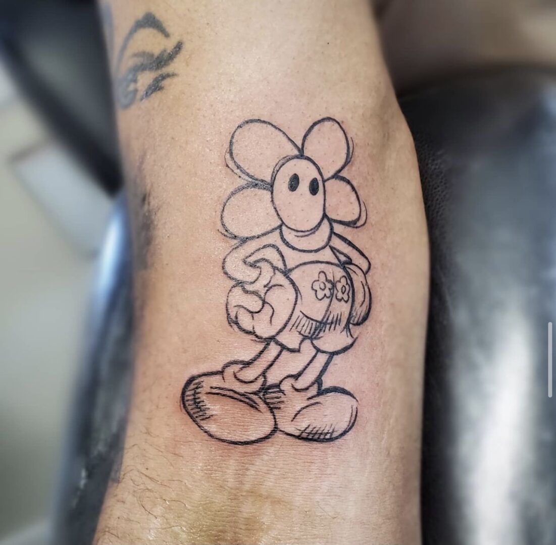 A mickey mouse tattoo is shown on the arm.