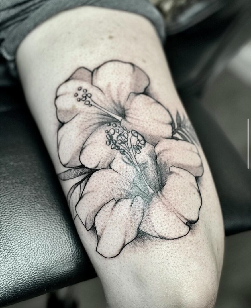 A black and white tattoo of a flower