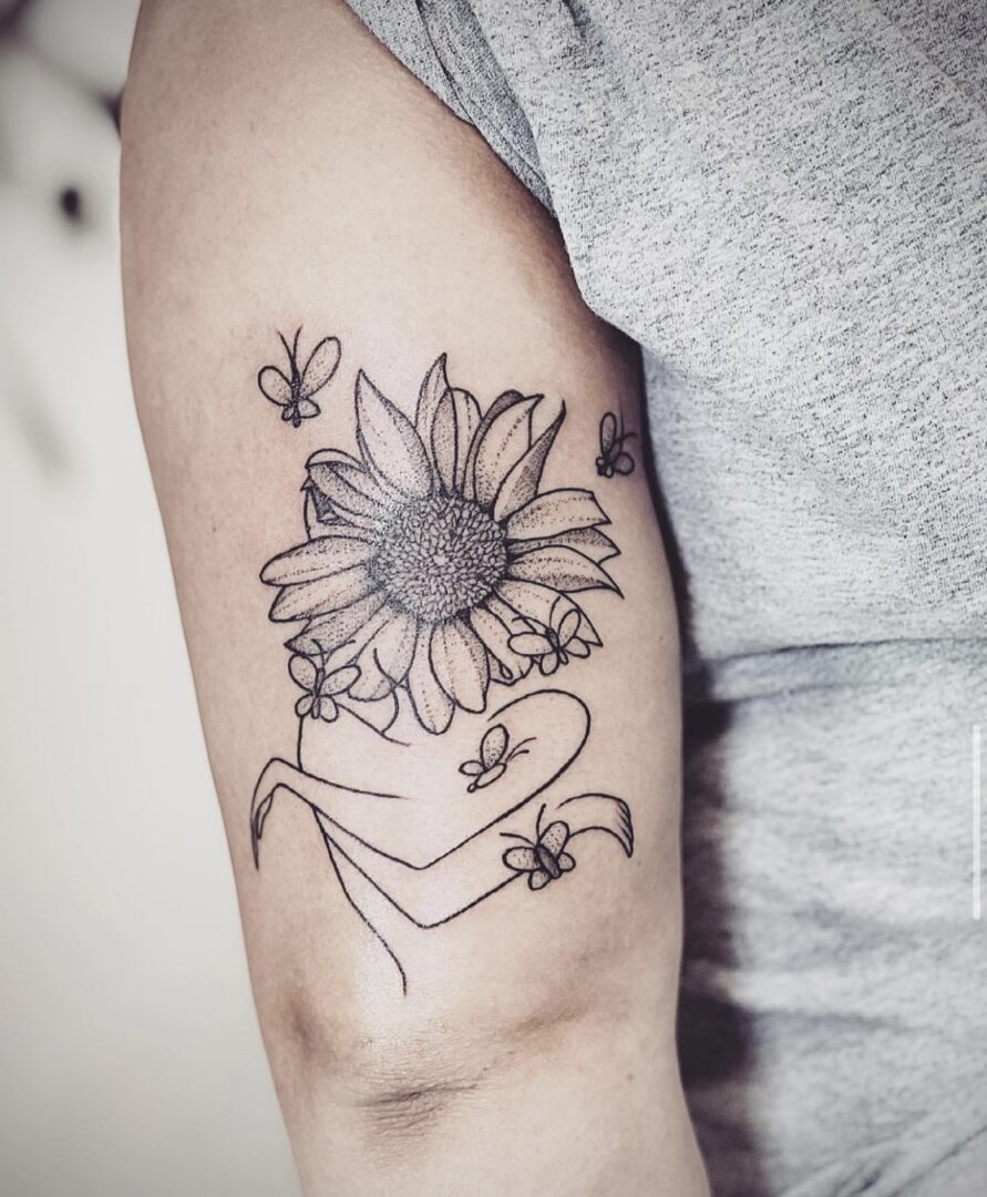 A tattoo of a sunflower and bees on the arm.