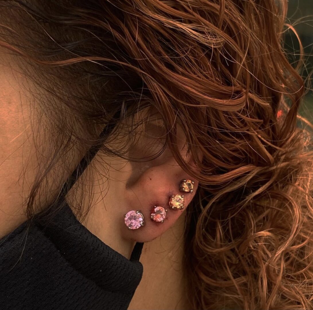 A woman with red hair wearing ear piercings.