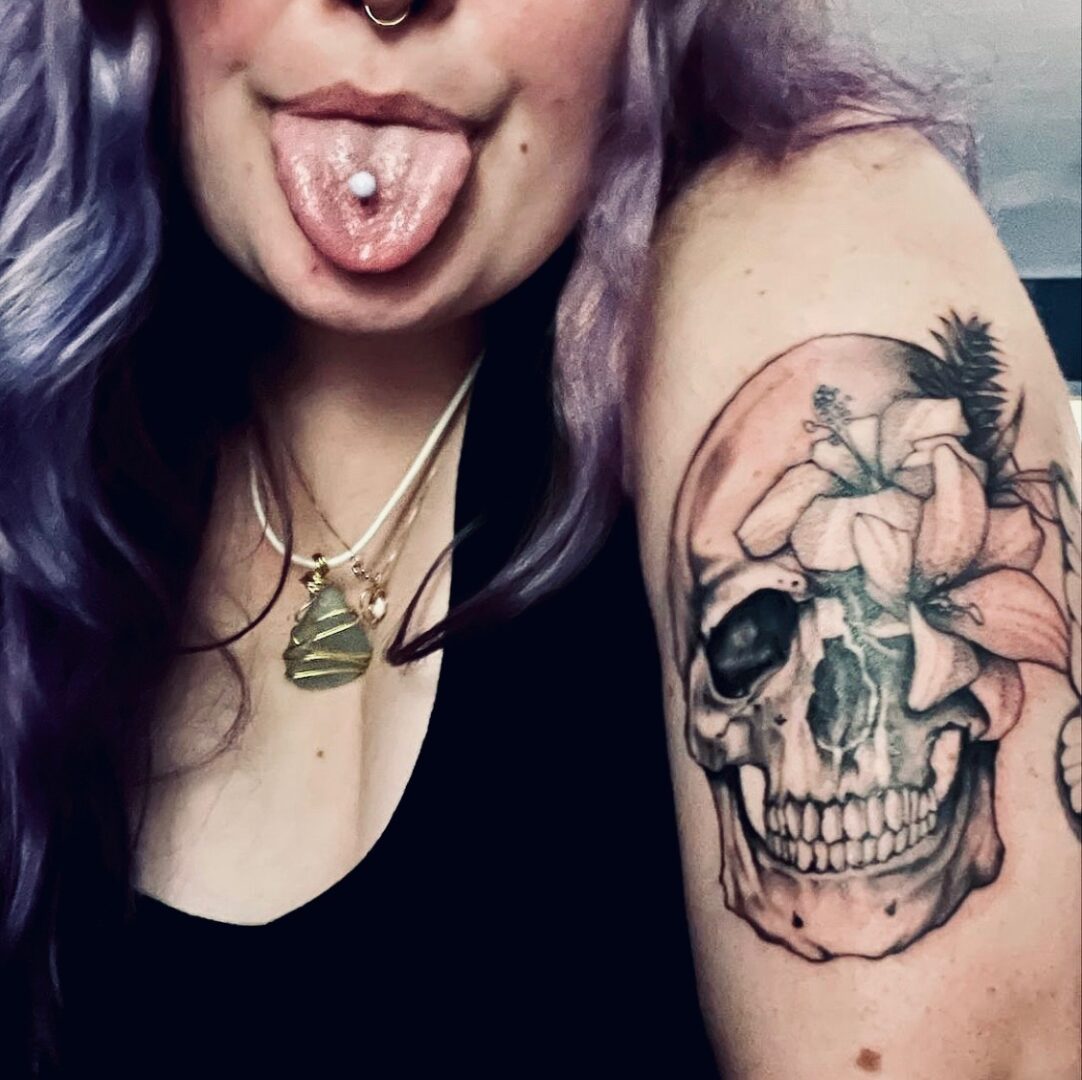 A woman with purple hair and a skull tattoo.