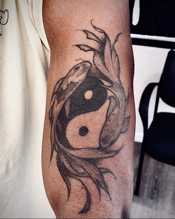 A tattoo of a fish and a bird on the arm.