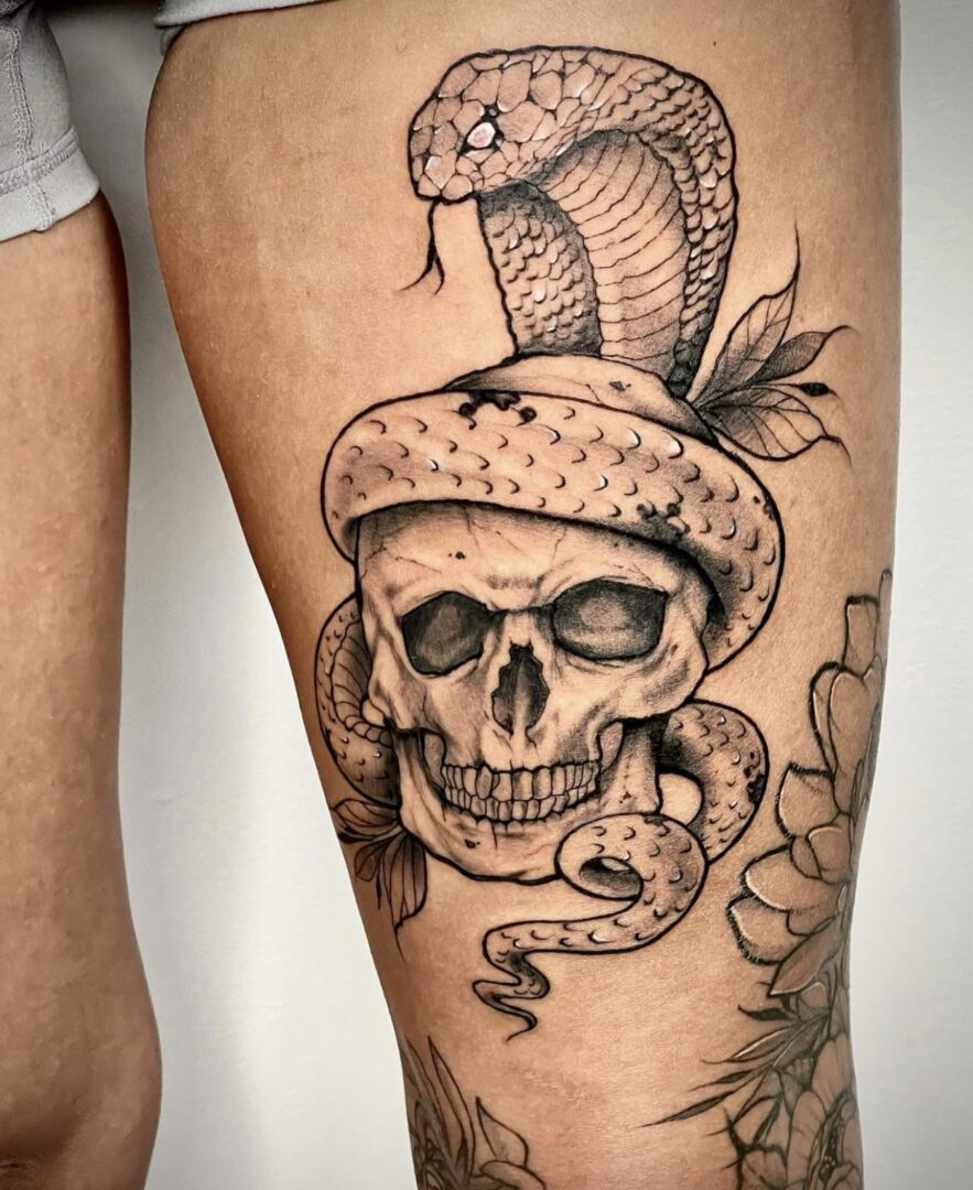 A tattoo of a snake and skull on the leg.