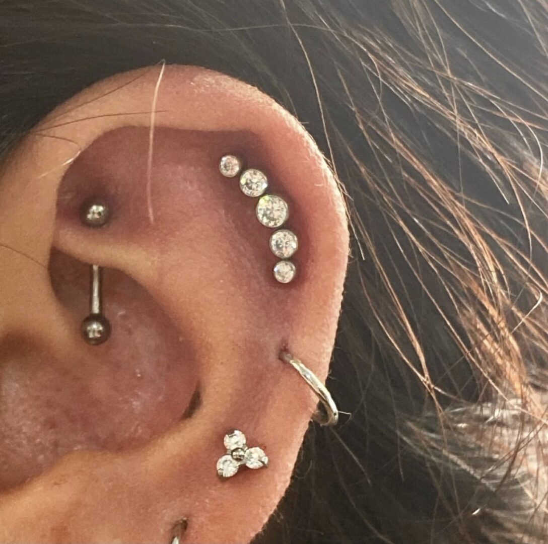 A woman 's ear with multiple piercings and a third piercing.