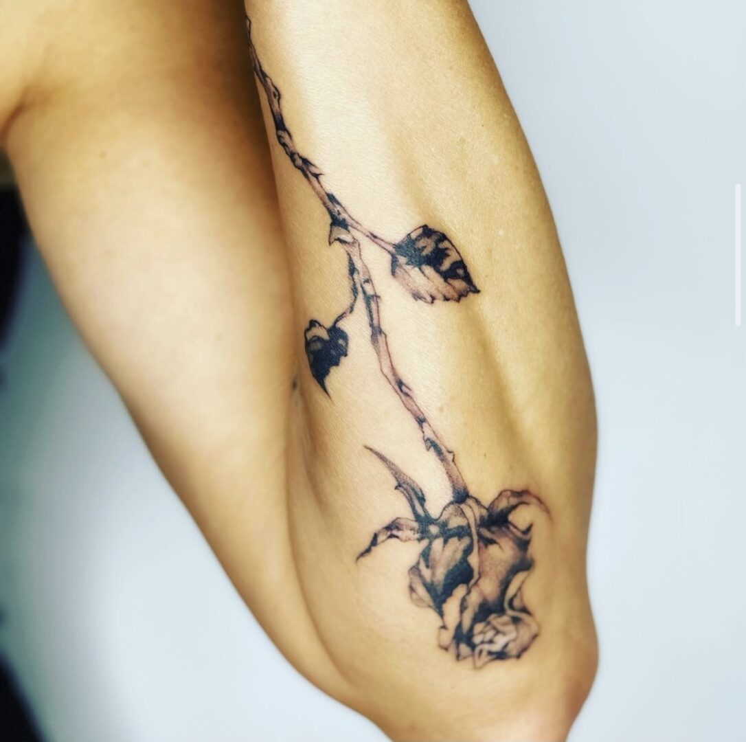 A tattoo of a branch with leaves on it.