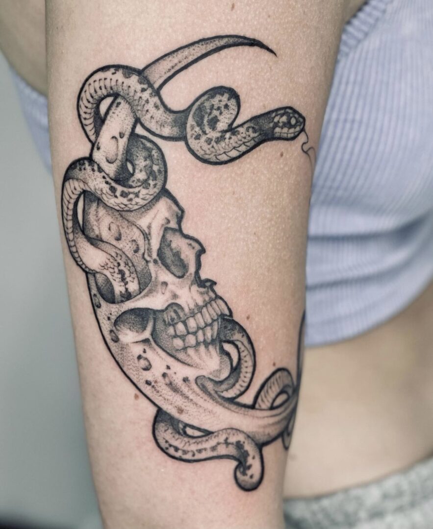 A woman with a skull and snake tattoo on her arm.